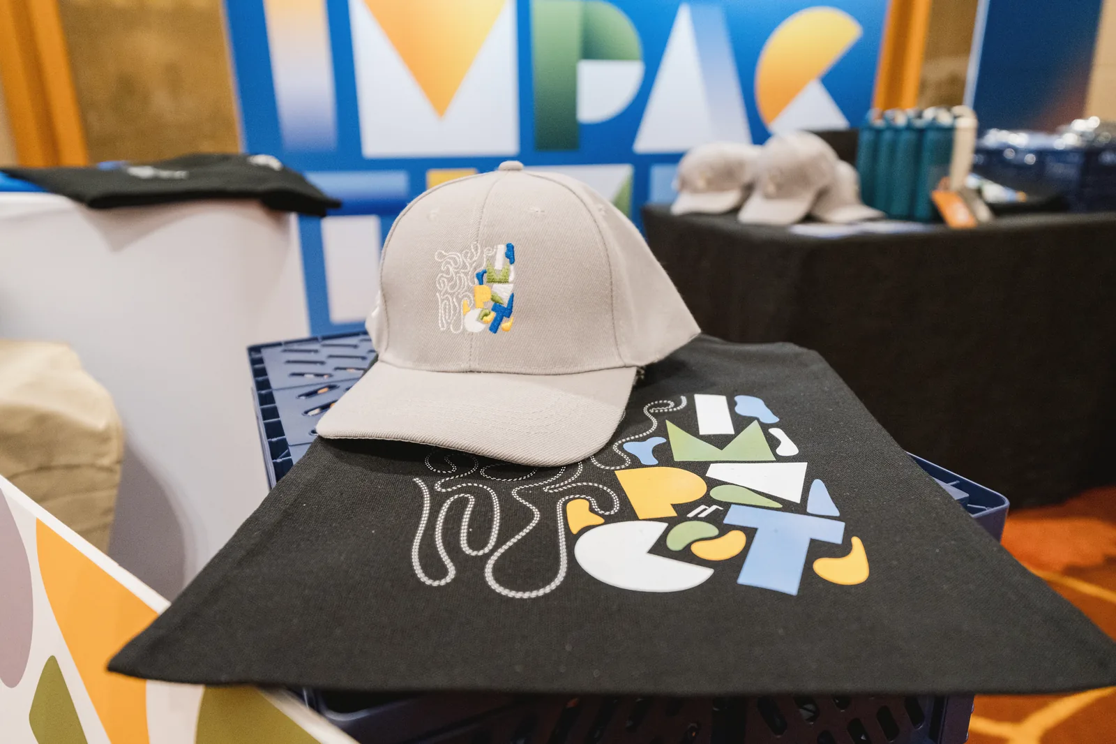 Summit merchandise: a cap and tote bag in front of the event backdrop