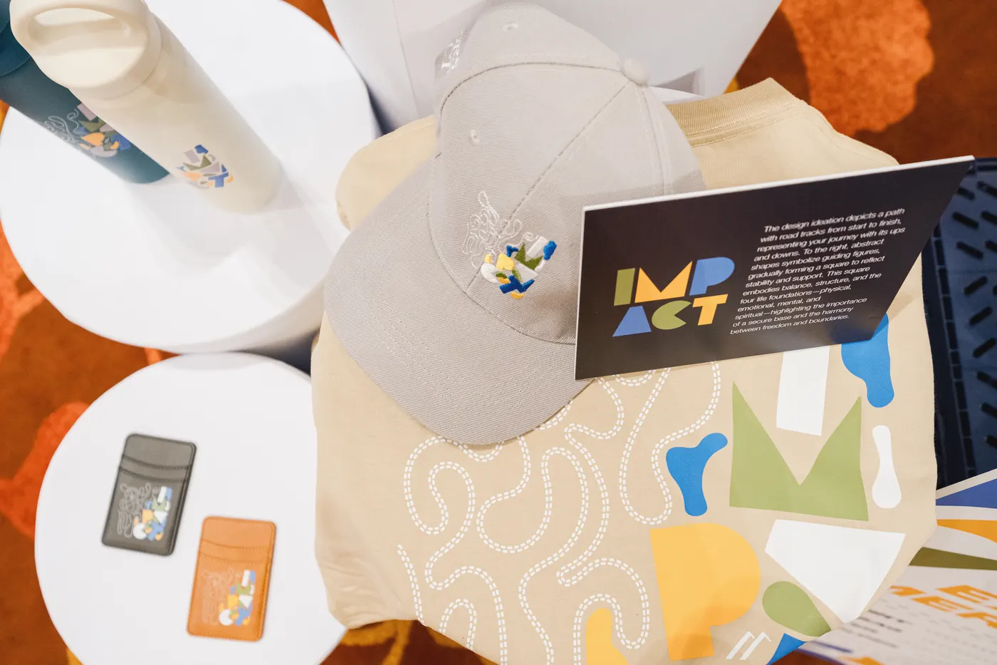 An embroidered cap and card holders with the IMPACT artwork