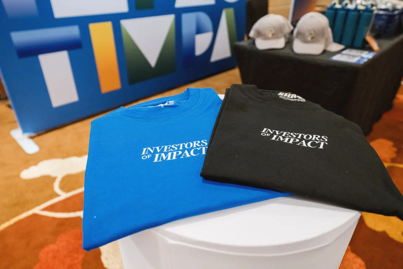Blue and black t-shirts printed with Investors of Impact